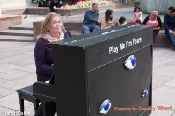 Hazel playing a piano in Canary Wharf